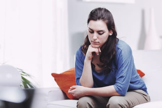 A young, sad, and thoughtful woman sits on her sofa, looking down. Depression is an illness, not a fault. It needs to be treated, and those who don't understand it underestimate or belittle it. She kn