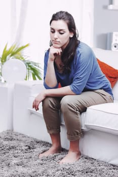 A young, sad, and thoughtful woman sits on her sofa, looking down. Depression is an illness, not a fault. It needs to be treated, and those who don't understand it underestimate or belittle it. She kn