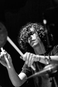 On a live stage, the fervor of a young drummer shines. With dark makeup and rocker mannerisms, he epitomizes the marriage of musical art and technique