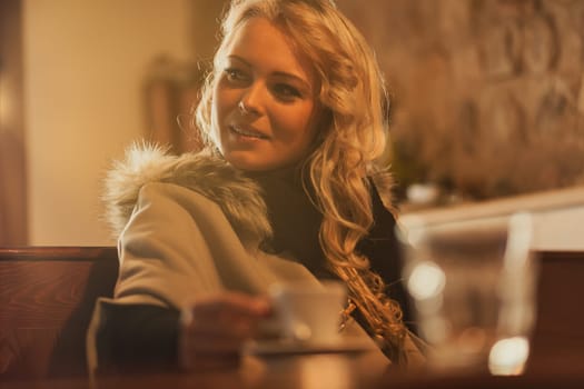 In sunlit European haven, young wanderer sips espresso's soul. Winter's chill forgotten wrapped in fur, beauty radiant. Solitude embraced, yet open to serendipity