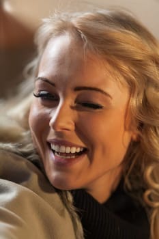 Young woman winks and laughs as she sits in a European bar and waits for a hot drink and her friends. How nice to be a tourist.