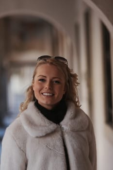 A blonde woman is sightseeing in a historic European city filled with cobblestone streets, archways, marble, and medieval or Gothic elements that have been preserved to appreciate millennial culture a