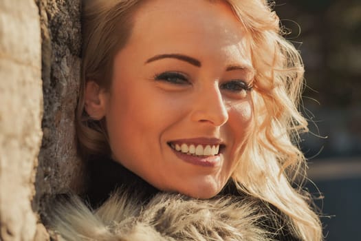 A blonde woman is sightseeing in a historic European city filled with cobblestone streets, archways, marble, and medieval or Gothic elements that have been preserved to appreciate millennial culture a