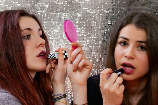 At a club mirror, two women with long dark hair and vivacious energy reapply lipstick. They're in the game of youthful allure, chasing the night's promises