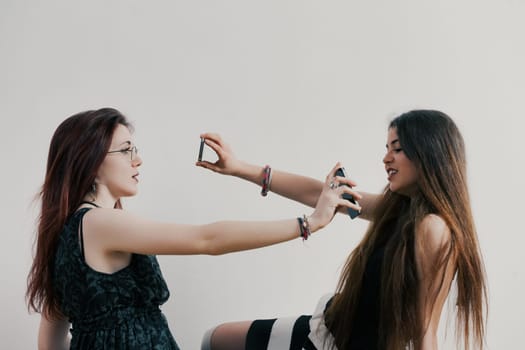 Communication breakdown amid crowds: two girls or young women grapple with the conflict of new media, smartphones, and a life online. Their focus diverts from tangible humans to screens, sidelining me