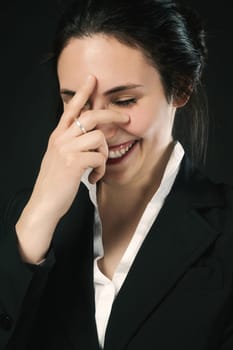 laughing woman in black business attire against a black background. Proven skill, evident value, and enduring beauty. Responsible for her happiness, she savors a joyful moment before reentering life's
