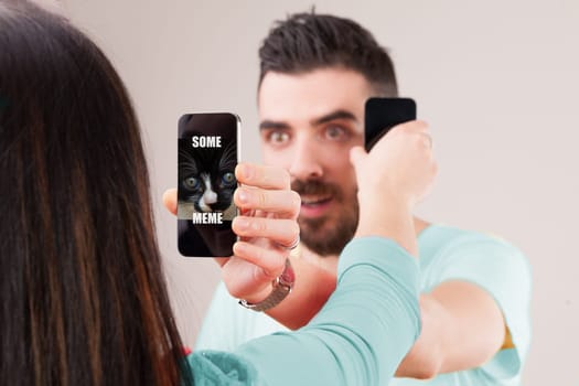 Forgoing conversation, a man and woman show screens to each other, sharing internet content rather than personal thoughts, echoing ancestors showing items and nodding, bypassing true communication and