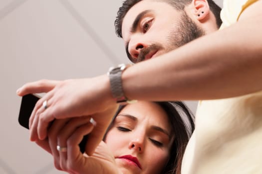 From below, man and woman engrossed in their phones, even when close. Apps, internet, instant messaging, and emails allow constant work, highlighting the double-edged sword of technology
