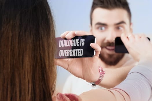 Instead of talking, a man and woman show each other screens, choosing non-verbal interaction. They prefer sharing internet content without personal dialogue, a modern equivalent of merely showing thin