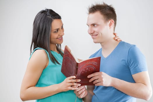 Pregnant woman and husband explore a booklet, selecting names. They uphold longstanding traditions and review the first ultrasound images, saved in their unborn child's album