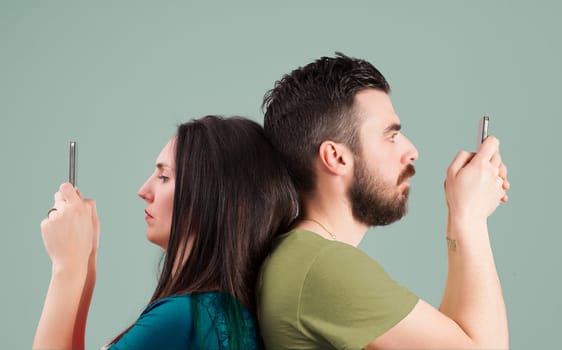 Man and woman, back-to-back, focus on their own screens. Together but apart, they ignore each other, embodying modern separation, engrossed in internet content in simultaneous solitude