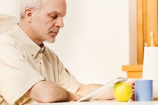 Aged man, at breakfast or during rest, delves into online world. Representing a generation that treasures tech advancements, he faces the universal challenge of sifting through information's credibili