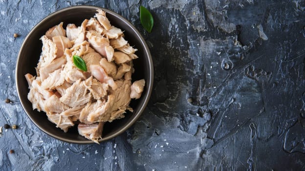 A bowl is shown filled with succulent meat that has been garnished with a fresh green leaf. The meat appears juicy and well-seasoned, while the green leaf adds a pop of color to the dish.