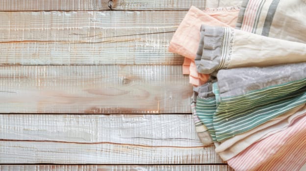 A collection of folded and unfolded clothes stacked haphazardly on top of a worn wooden floor. The garments vary in color and texture, creating a messy yet functional scene.