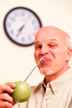 Apple in focus. An elderly man believes the proverb: an apple a day keeps the doctor away. In his kitchen, he's a playful joker but values fruit quality while savoring each vitamin drop