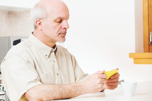 Utilizing devices, elderly man seeks updates during meals. Respecting technology's gifts, he's from an era that doesn't trivialize them. The maze of finding genuine versus deceptive sources remains
