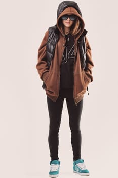 The woman sports a streetwear style with sunglasses, a hoodie, and sneakers.