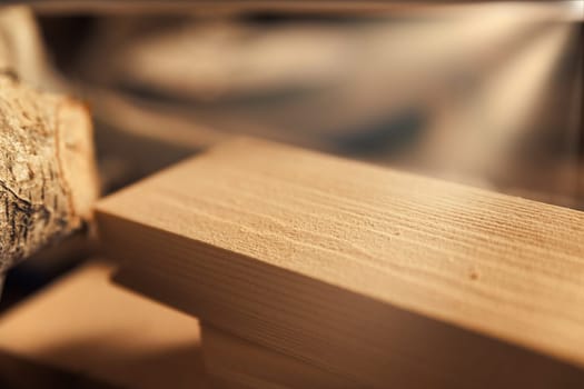 Rays of light streaming in through the large window of a carpentry shop hit rough-hewn boards and pieces of wood, ready for further processing, materials to be touched.