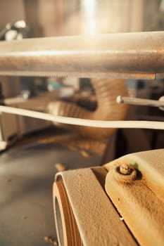 Small detail in focus of an adjustment, knob or in an element of woodworking tools, while the rest remains out of focus. Atmosphere and light in a craftsman carpenter's workshop. Wood and metal.