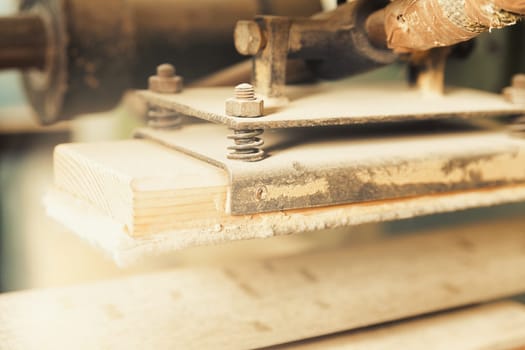 Small detail in focus of an adjustment, knob or in an element of woodworking tools, while the rest remains out of focus. Atmosphere and light in a craftsman carpenter's workshop. Wood and metal.