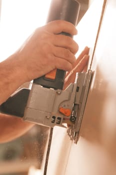 craftsman's hand with a cutting tool or sanding all seen against the light. Moment of action at work