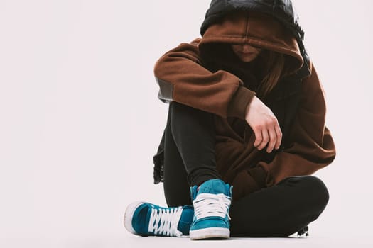 Woman seated in contemplation, emotions concealed by hoodie