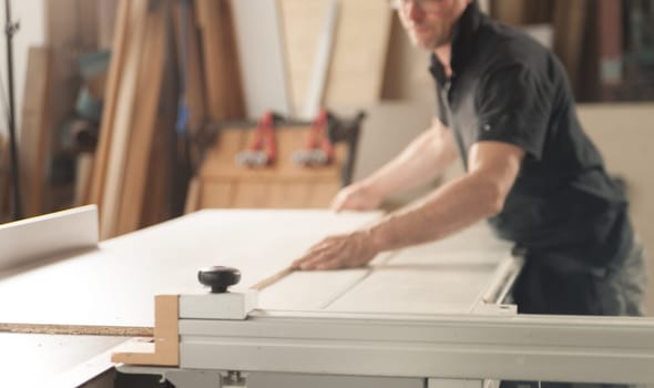 Craftsman at work in his own workshop. One man works with proper tools, shelves to saw, sand, plane, and finish wooden parts and surfaces.