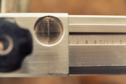 Small detail in focus of an adjustment, knob or in an element of woodworking tools, while the rest remains out of focus. Atmosphere and light in a craftsman carpenter's workshop. Wood and metal.