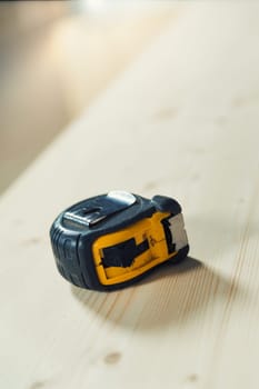 A carpenter's tape measure resting on a rough wooden surface, like a board, ready to become something else. Precision is the opposite of approximation.