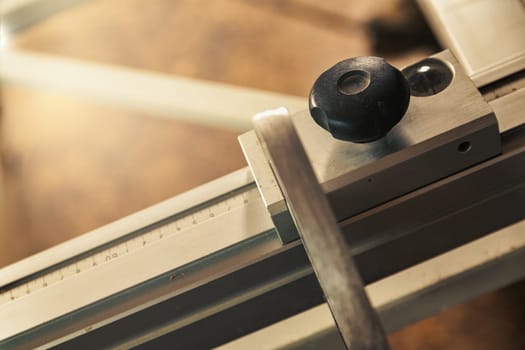 Small detail in focus of an adjustment, knob or in an element of woodworking tools, while the rest remains out of focus. Atmosphere and light in a craftsman carpenter's workshop. Wood and metal.