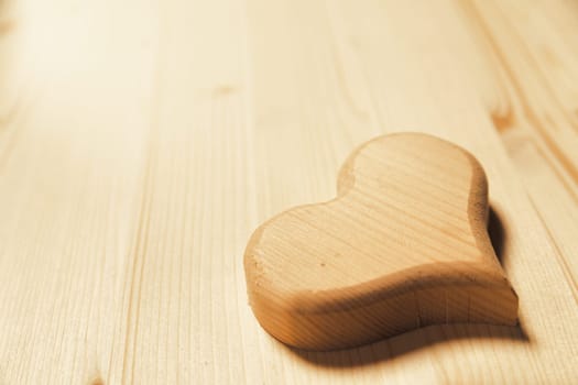 Precisely carved heart positioned in the lower right corner on a wooden surface. Great background with lots of COPYSPACE for both Valentine's Day and love in general.