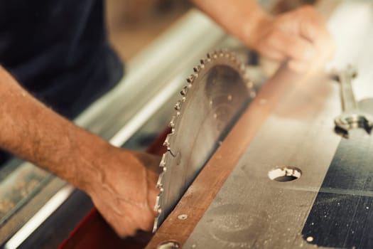 A close-up shot in focus of the toothed blade of a circular saw stopped for setup by the carpenter. Being a skilled artisan in this century means using modern machinery for tasks as old as humanity