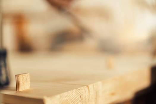 Focused detail in wood. A small dowel seems to be looking at the expanse of the board, blurred. Excellent background full of copyspace on woodworking topic.