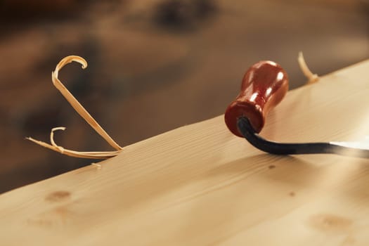 Curl in focus against the blurred background of a sawmill. is the incomplete result of a cut with a hand tool on a board, made by a craftsman carpenter.