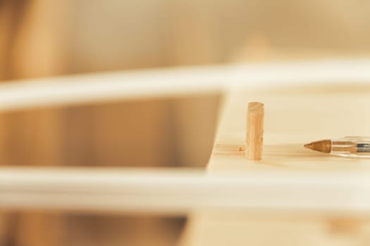Pen tip near working wood. In focus is only the dowel ready to fasten various parts of a piece of furniture and the tip of a cheap but excellent ballpoint pen.