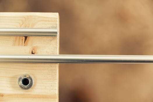 Small detail in focus of an adjustment, knob or in an element of woodworking tools, while the rest remains out of focus. Atmosphere and light in a craftsman carpenter's workshop. Wood and metal.