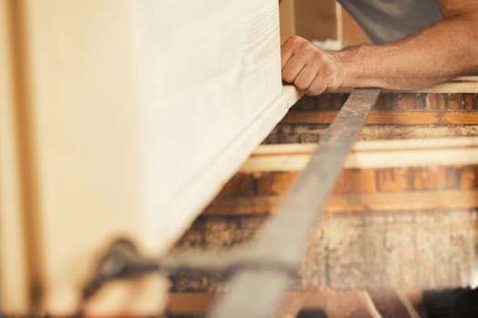 Strong carpenter's hands hold, guide, restrain, push, and move lumber while working with powerful cutting machines in his workshop. Image conveys strength, skill, and risk-taking expertise