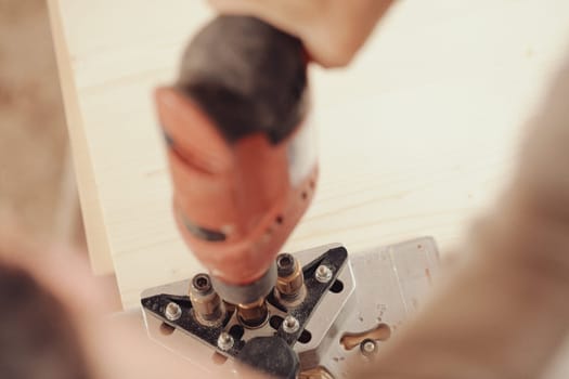 Detail in focus of a drilling jig used by the woodworker in his craft workshop. Although they can be self-made the multi-pattern carpenter's drilling jigs are convenient and professional.