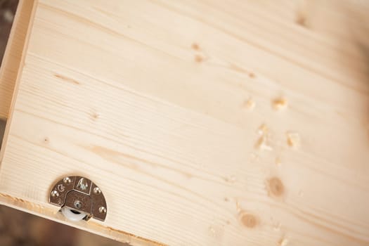 Metal detail inserted into a wooden component that will form a piece of furniture handcrafted in a carpenter's workshop. Wheel that will slide a drawer or shelf.