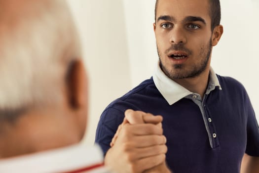 Intense gaze of a young man in an arm-wrestled handshake, embodying strength and respect