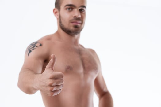 Confident gaze from a tattooed man displaying approval with a thumbs-up gesture