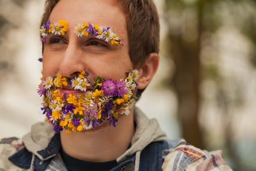 In the wild, a man stands out. His unique trait? Facial hair made of blossoms. This look, whether reality or perception, speaks volumes about his deep connection to nature's charm and calm