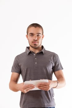 Concentrated young adult with a tablet, standing against a white background