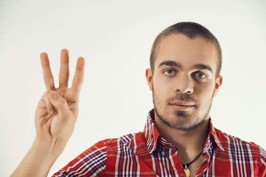 Confident young adult holds up three fingers, indicating number