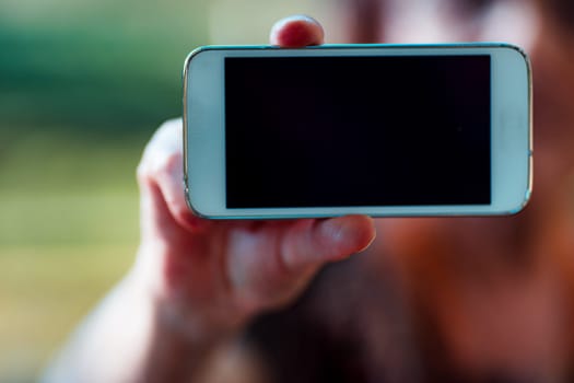Outside, an elderly lady's hands, bearing signs of arthritis and fluid buildup, present a smartphone with a blank screen ideal for COPYSPACE. Apps for telehealth and loved ones are beneficial
