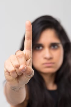Blurred image of Indian girl. In the foreground, perfectly in focus, the index finger of her hand extended toward us as a warning, admonition or categorical denial. No way.
