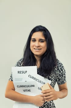 cheerful woman with dark hair is seen holding multiple copies of her 'CURRICULUM VITAE' and a smartphone. Her dress features a black and white rose pattern, suggesting professionalism with a hint of e