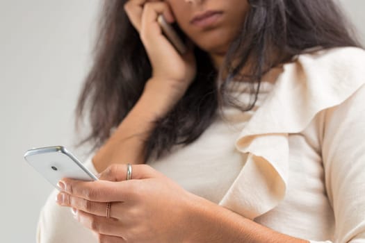 With a smartphone pressed to her ear and another in hand, the subject is engrossed in modern communication, her flowing attire adding an air of grace