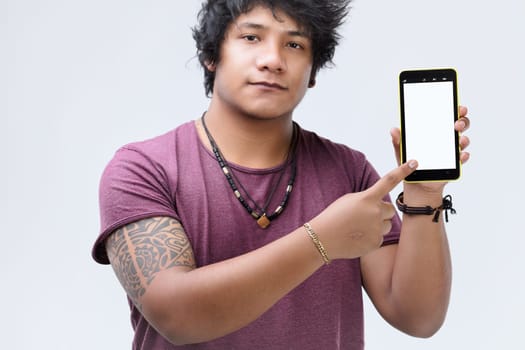 With a confident demeanor, the man with tan skin and curly hair points at a blank-screened, yellow-bordered smartphone