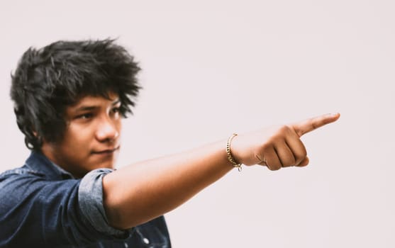 Amidst a muted background, the man's gesture is powerful, pointing with determination, his wild hair and denim shirt adding to his character